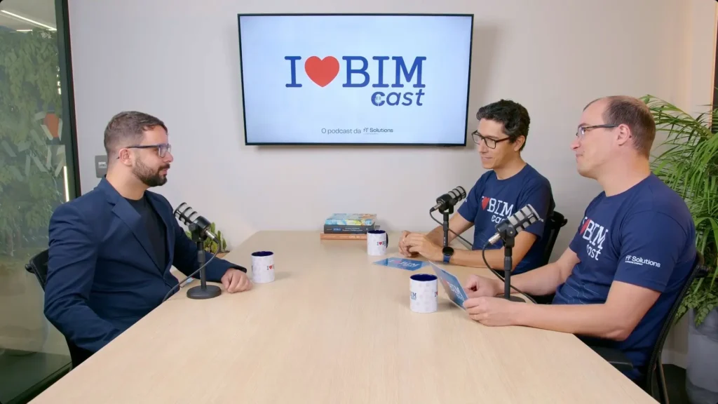 Três homens sentados à mesa de reunião gravando o podcast I Love BIM Cast, com microfones e a logo do programa exibida na TV ao fundo